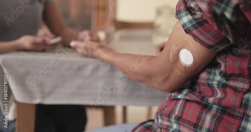 Asian daughter measuring blood sugar level to her mother for diabetes control - Family lifestyle, disease and medicine concept