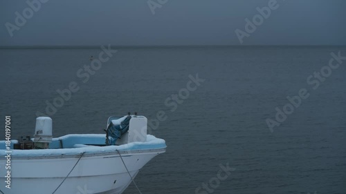 岸辺に陸揚げされた小さな漁船のある雪景色