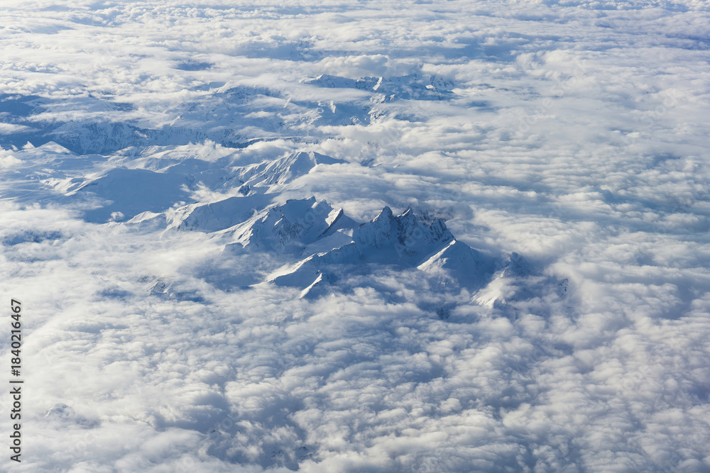 Fototapeta premium Aerial View of Majestic Snow Capped Mountain Summits Rising Above Clouds in Europe