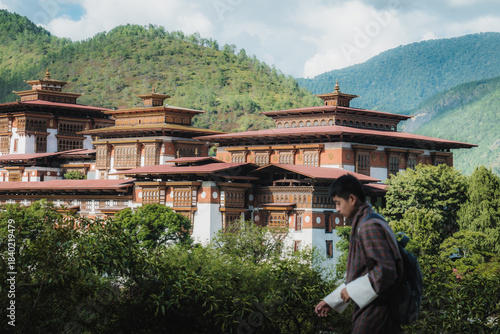 Punakha, Bhutan - 19 September 2025: View of a man walking in the foreground, with the grandiose Punakha Dzong rising majestically against the backdrop of verdant hills.