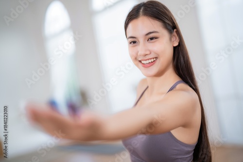 Free Download Woman stretches her hand forward with a smile during a yoga session in a bright studio with large windows and wooden floors - GFXLoad