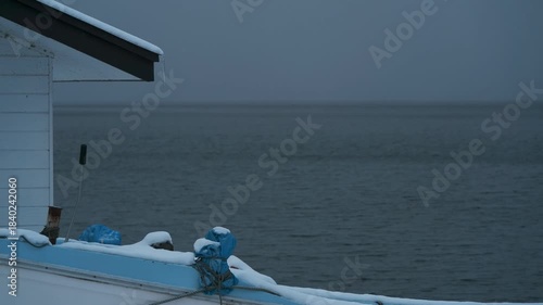 岸辺に陸揚げされた小さな漁船のある雪景色