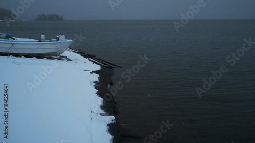 岸辺に陸揚げされた小さな漁船のある雪景色
