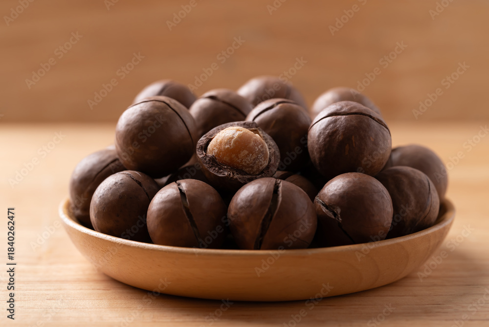 Obraz premium Macadamia nuts in a bowl on wooden background