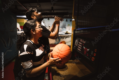 friends enjoying an indoor basketball arcade game together at a vibrant gaming zone.