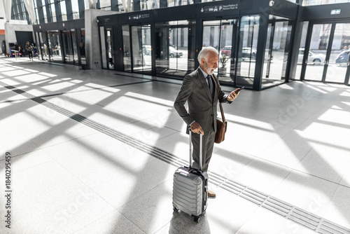 Elderly Businessman Traveling with Suitcase in Modern Lobby