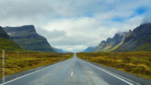 Endless road through dramatic icelandic valley with mountains and cloudy sky