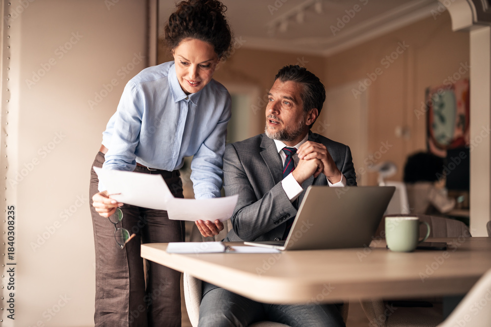 Fototapeta premium Business Professionals Collaborating and Discussing Reports in Modern Office Setting