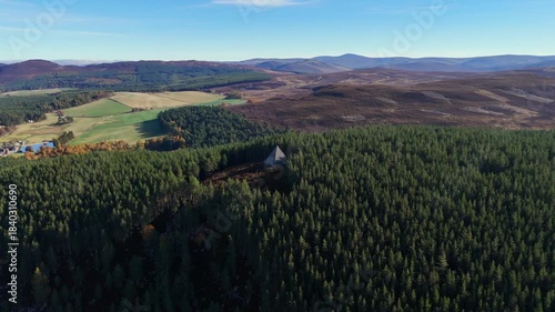 Aerial view of a pyramid situated in dense lush forest perched on a hill.
