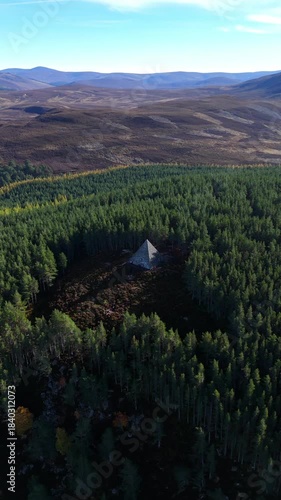 Aerial view of a pyramid situated in dense lush forest perched on a hill.