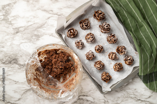 Individual, pinecone desserts made of brownies and whipped cream cheese sprinkled with powdered sugar in a pan. Glass bowl with brownie cream cheese dough.