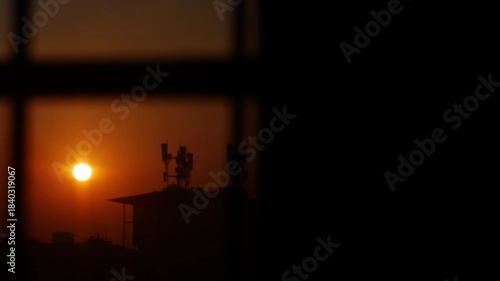 Beautiful golden sunset sky over city skyline with communication towers viewed through window silhouette frame, evening technology concept.