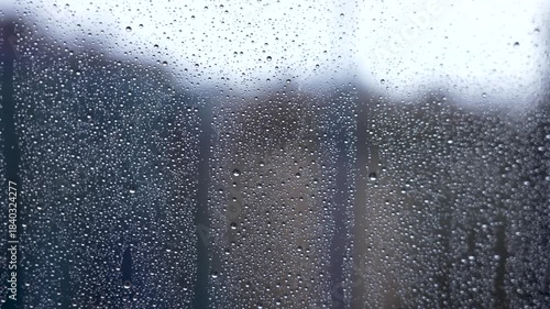 Glass of house window covered with raindrops on a foggy cloudy morning