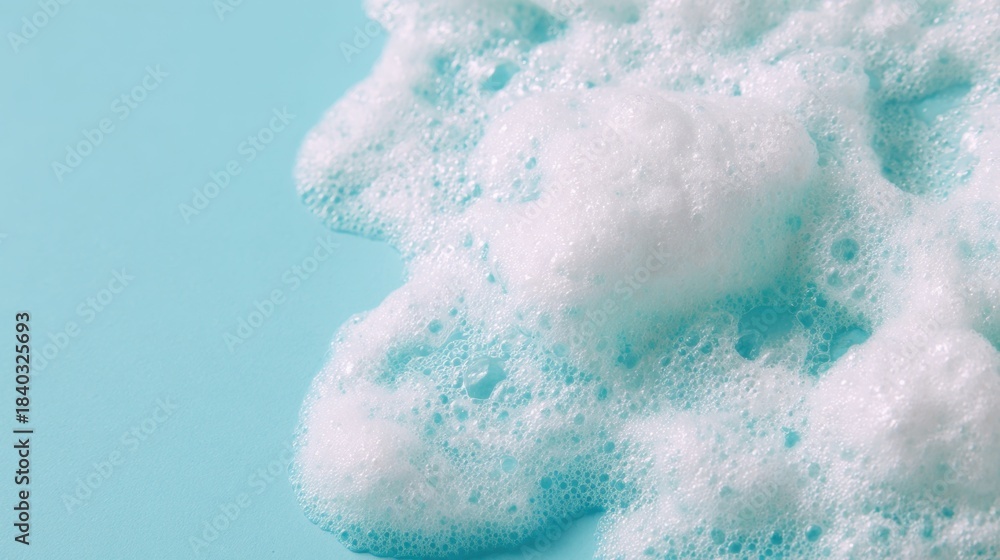 Fototapeta premium White foam spreads over a blue surface during a cleaning activity