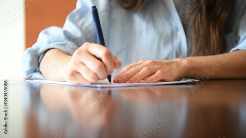Woman's hand signing document on desk