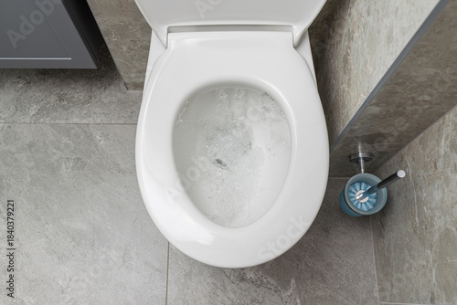 Water is running in the toilet in the bathroom, view from above.