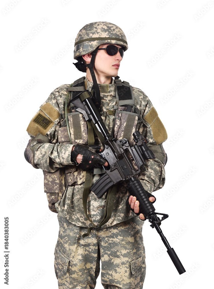 Obraz premium An American soldier stands in full gear with his rifle lowered