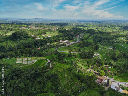 Aerial View Of Terraced Rice Fields Under Clear Blue Sky, Winding Contours Of Emerald Paddies Cascading Down