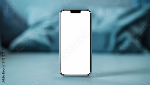 Modern smartphone with blank screen is positioned on surface, surrounded by soft, blurred bedding in background. sleek design and minimalistic appearance evoke sense of technology and simplicity