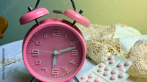 Pink alarm clock and pills on a lace backgound 