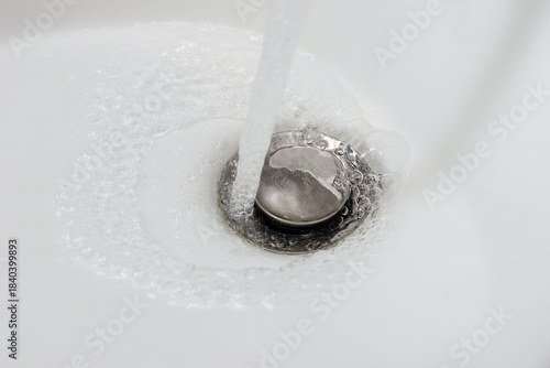 Water runs from the faucet into the bathroom sink, close-up.