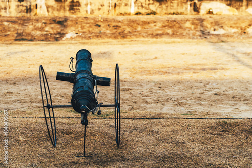 Replica of ancient cannon made of black painted steel on field can emits smoke and makes a sound like a real bullet being fired using an electronic system to accompany the outdoor retro performance.
