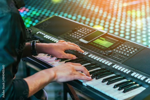 Hands of male musician press digital electronic keyboard synthesizers on concert stage. Pianist man hands play the keys of electronic piano. Piano music pianist hand playing. Selective focus on hand.