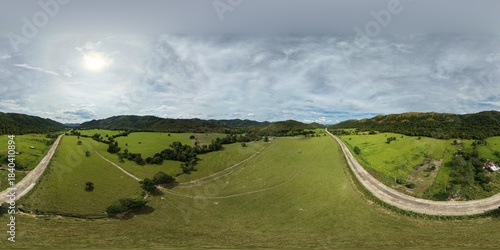 Drone 360 panoramic view of vast green pastureland and savanna with rural road, scattered trees and rolling hills at Yulo King Ranch on Busuanga Island near Coron, Palawan, Philippines.