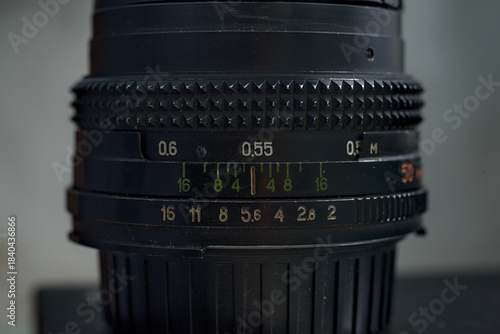 Photo of black metal manual lens showing focus aperture rings, green and white distance and f-stop markings.