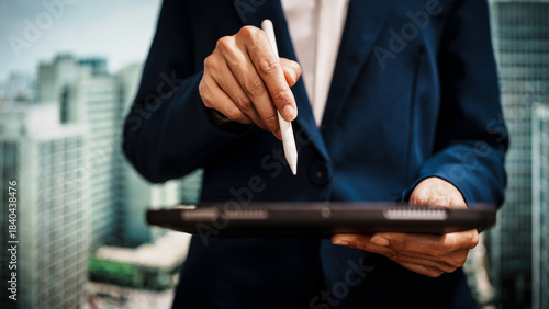 Professional business woman holding digital tablet against city skyline, real estate assets, investment opportunities, land rights, long-term wealth through stable, high-value immovable properties.