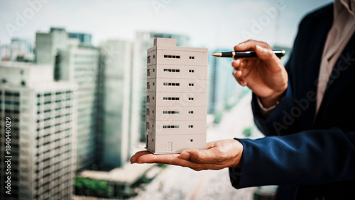 Business woman presenting miniature building model city skyline, real estate assets, property development,land rights,long-term investment, rental income, stable value growth of immovable properties.
