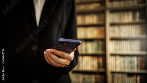 professional woman using smartphone inside law library, legal consultation, attorney responsibilities, case preparation, negotiation skills, modern legal practice supported by digital technology.