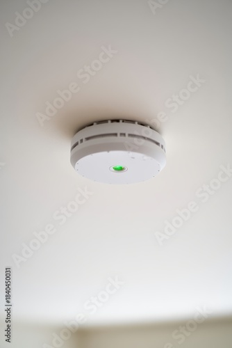 Ceiling-mounted smoke detector with illuminated green LED and textured ceiling