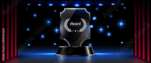 Glass award trophy on stage with red curtains and spotlights.