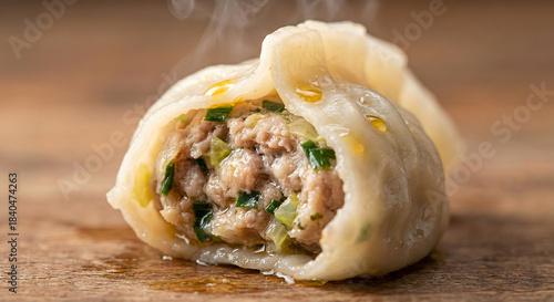 Close-up of a steaming, hot Chinese dumpling cut open, showing pork and chive filling.