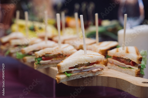 Close-up of sliced triangle sandwiches on a wooden buffet board