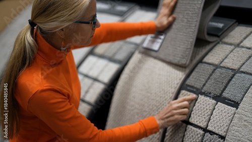 A mature woman is shopping in a large hardware store while looking at various fabric samples for home renovation projects