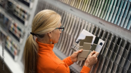 Canvastavla Mature woman looks at paint samples while shopping in a hardware store for home