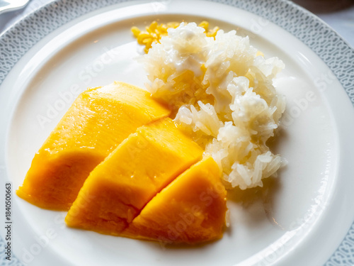 Mango sticky rice with coconut milk topping, famous Thai dessert, serve on white dish in luxury restaurant