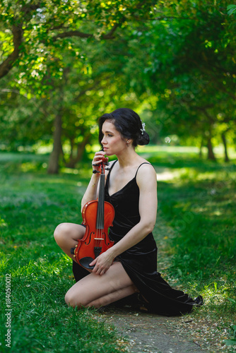Violinist in a park setting with a contemplative pose