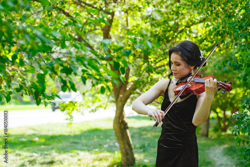 Violinist playing in a lush green outdoor setting