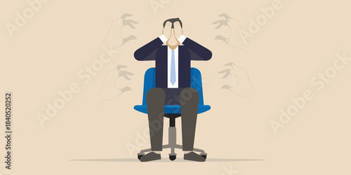 A stressed businessman sits in a chair covering his face with his hands