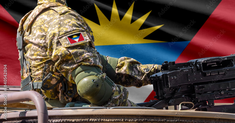 Obraz premium Antigua and Barbuda flag with soldier at machine gun turret in front of it. Closeup side view.
