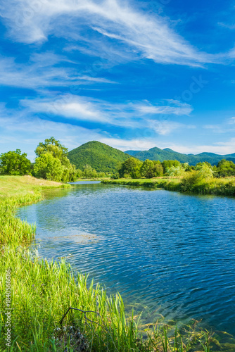 Beautiful river Gacka flowing between the green meadow fields in Lika region, Croatia 