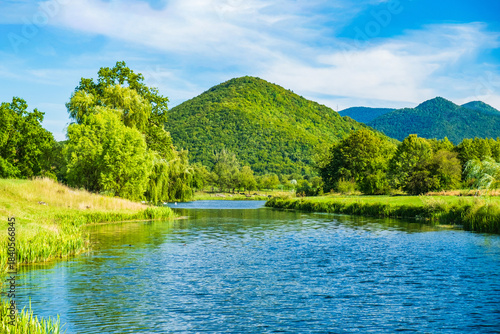 Beautiful river Gacka flowing between the green meadow fields in Lika region, Croatia 