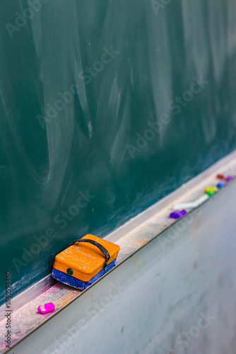 黒板に並ぶ黒板消しとチョークの学校教室の静かな一場面／Eraser and chalk on classroom blackboard in quiet school scene