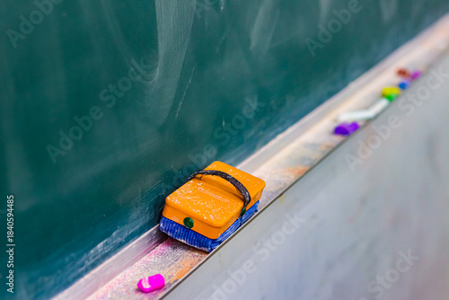 黒板に並ぶ黒板消しとチョークの学校教室の静かな一場面／Eraser and chalk on classroom blackboard in quiet school scene