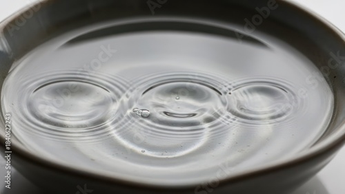 Clear water in gray bowl with ripples close up minimalist design