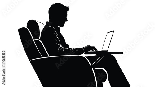 A silhouette of a man casually working on a laptop while relaxing in a comfortable chair