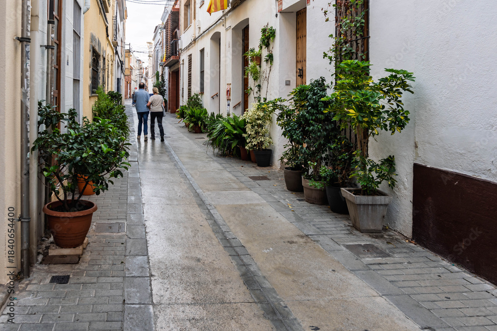 Obraz premium Tourists strolling through a charming alleyway in a white Spanish village on a sunny day.